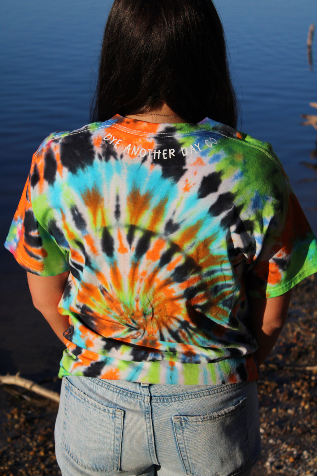 Person wearing a colorful tie-dye t-shirt with a blue background