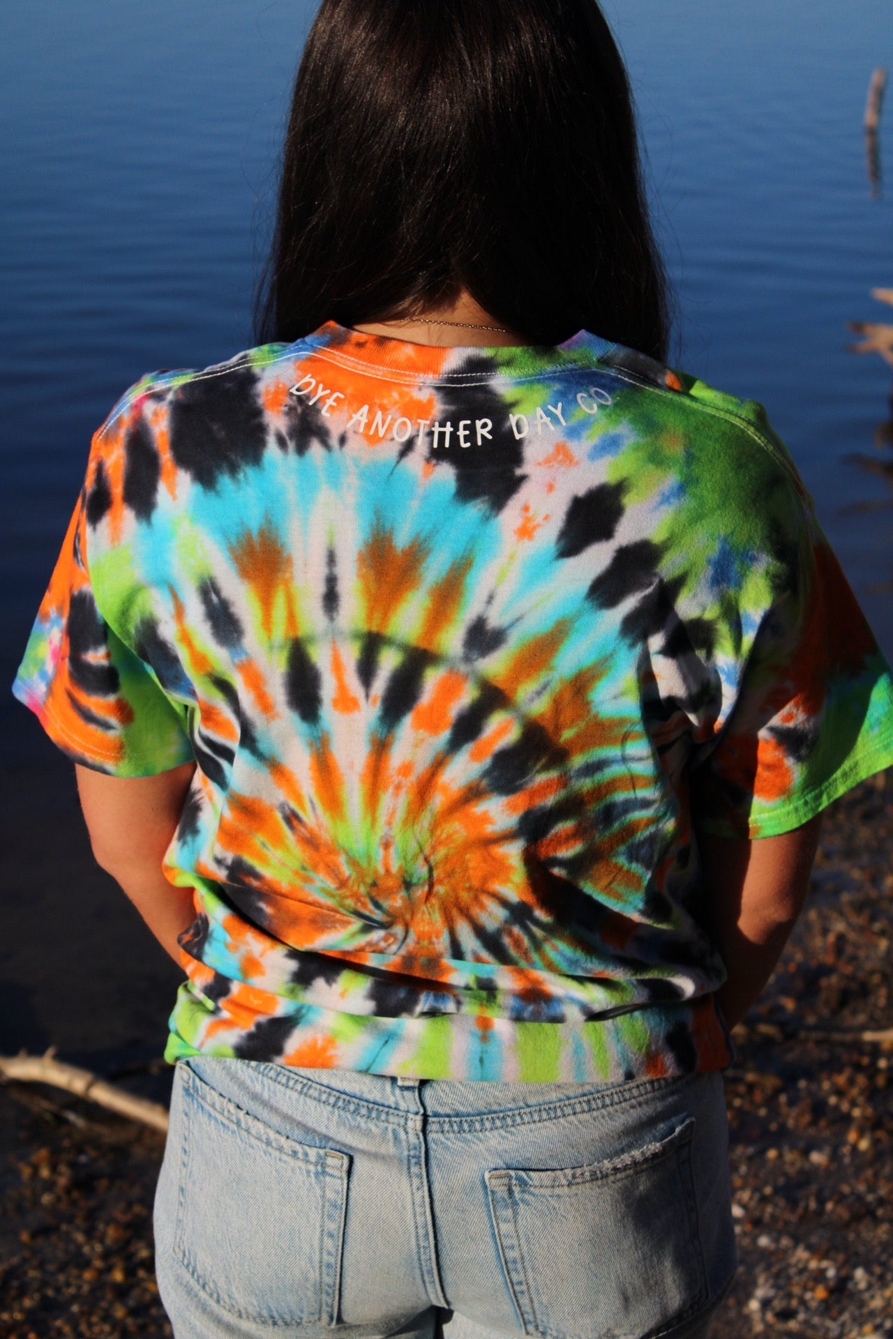 Person wearing a colorful tie-dye t-shirt with a blue background