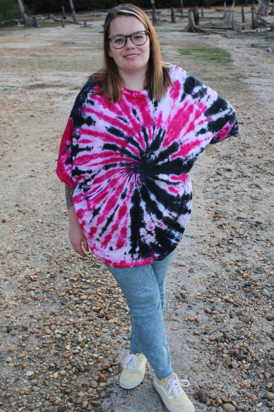 Person wearing a tie-dye shirt standing on a gravel path